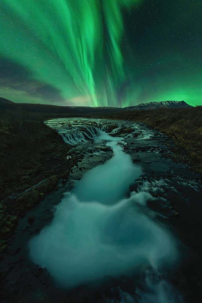 The Northern lights and flowing water in Brúarfoss, Iceland.
