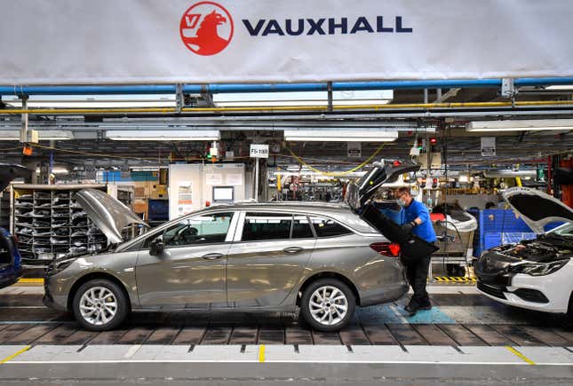 View of the Astra production line at the Vauxhall Ellesmere Port plant where a worker in a blue shirt places a mat in car boot.