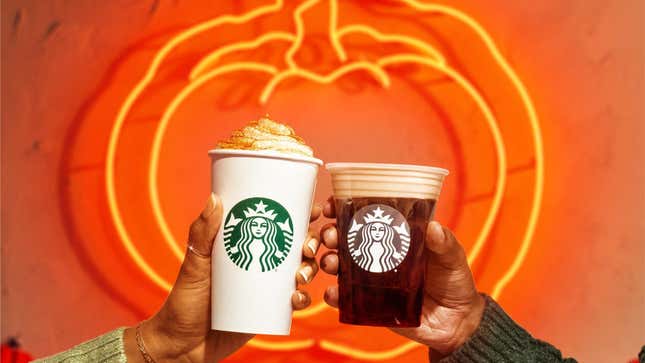 Hands toasting Starbucks Pumpkin Spice Latte and Pumpkin Cream Cold Brew in front of pumpkin neon sign