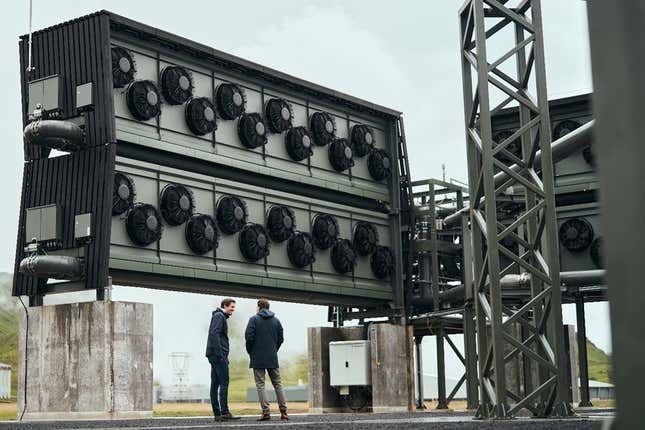photo of two people in front of big carbon capture machine