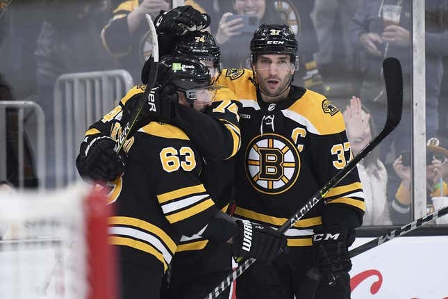 Apr 11, 2023; Boston, Massachusetts, USA; Boston Bruins left wing Brad Marchand (63) and center Patrice Bergeron (37) congratulate left wing Jake DeBrusk (74) after scoring a goal during the third period against the Washington Capitals at TD Garden.