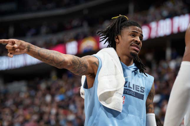 Memphis Grizzlies guard Ja Morant talks with teammates on the bench in the first half of an NBA basketball game against the Denver Nuggets, Friday, March 3, 2023, in Denver.