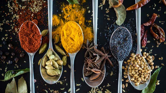 Aerial view of various spices piled on teaspoons