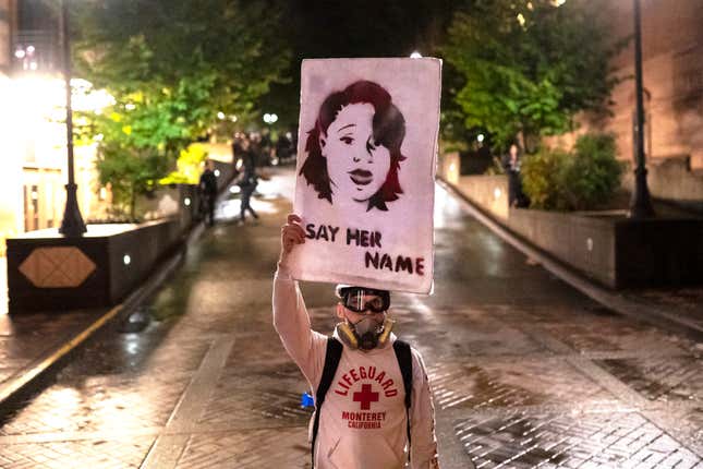 A protester walks toward Portland police with a sign honoring Breonna Taylor on September 23, 2020 in Portland, United States.