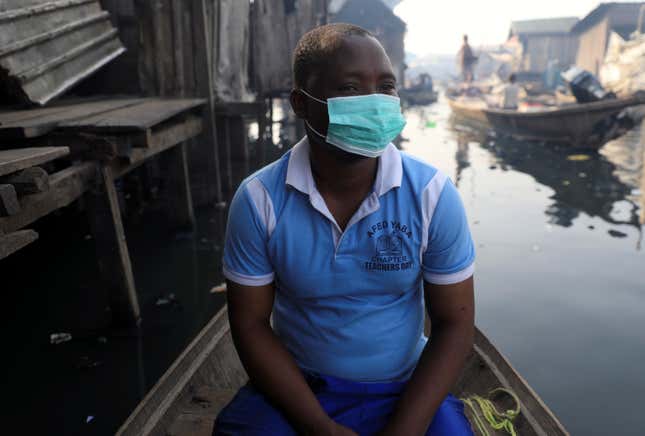 A man wearing a face mask sits in a traditional canoe at the Makoko community in Lagos, Mar. 9, 2020.
