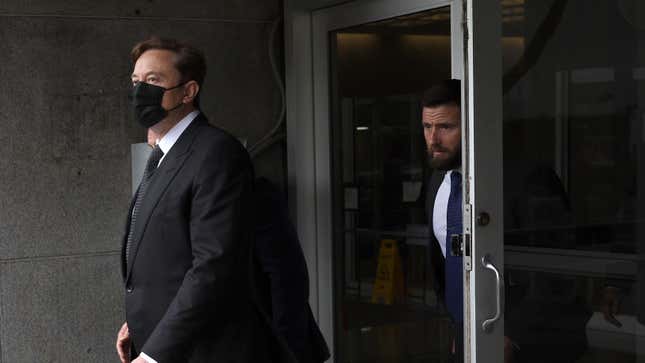 Elon Musk walking out of court wearing a mask and looking out to the side