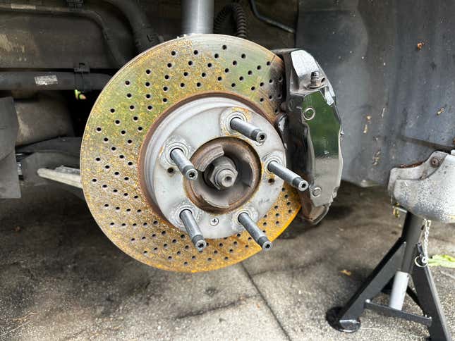 A mildly rusty brake rotor and black brake caliper are shown.