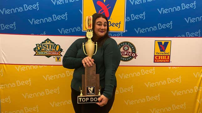 Winner of hot dog contest posing with giant hot dog trophy