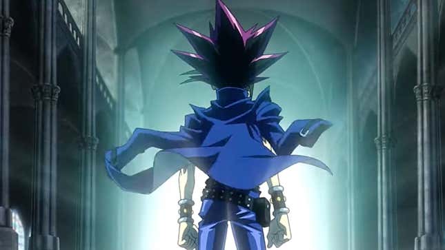 Yugi, his blue jacket draped across his shoulders, strikes a pose in a long, ornate hallway.