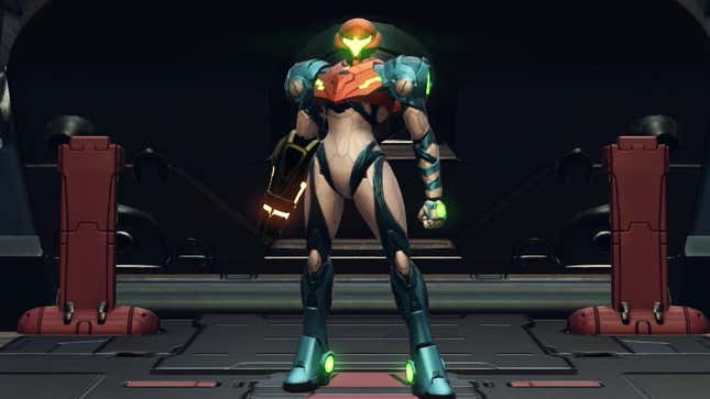 Samus Aran stands facing the viewer in a dimly lit sci-fi facility of some kind.