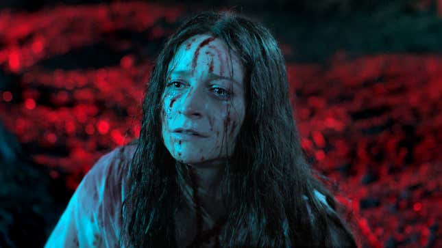 A woman with blood splattered on her face in front of a red background looks distraught in a scene from the movie Censor.