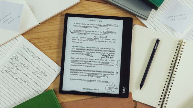 The Kobo Elipsa 2E on a wooden desk surrounded in paper notebooks, with the Kobo Stylus 2 just off to the side of it.