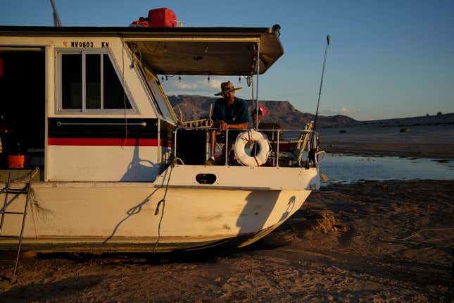 A man sits on his stuck houseboat in Lake Mead.