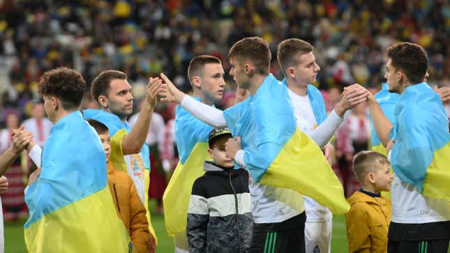 Players wearing Ukrainian flags embrace prior to the friendly match between KP Legia Warszawa and Dynamo Kyiv in Warsaw as part of the series “Match for Peace! Stop the War!”