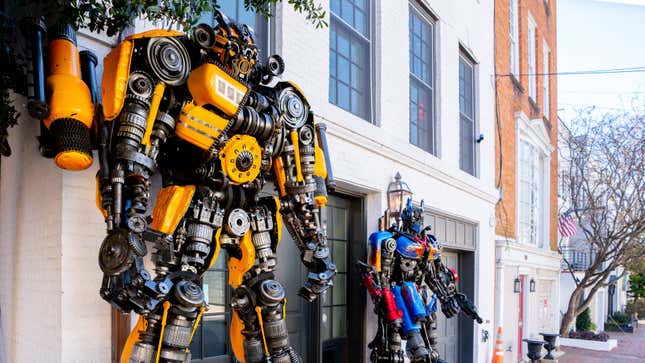Optimus Prime and Bumblebee statues stand near a residential door.