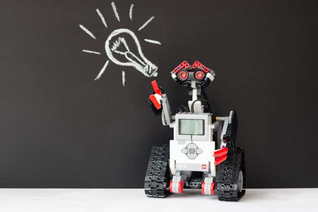 A Lego Mindstorms robot pointing to a chalk drawing of a lightbulb