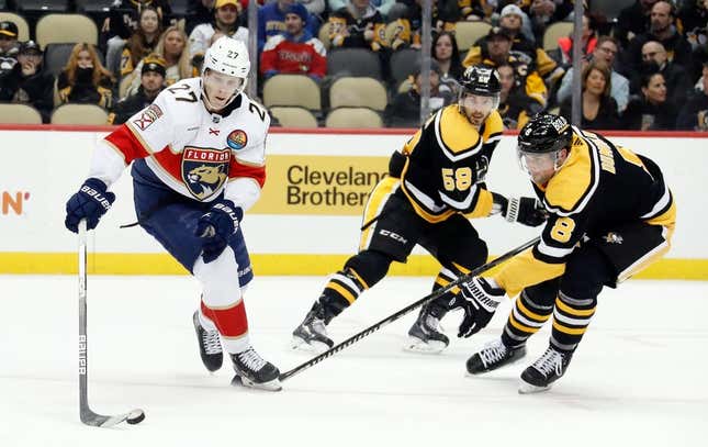 Jan 24, 2023; Pittsburgh, Pennsylvania, USA;  Florida Panthers center Eetu Luostarinen (27) moves the puck as Pittsburgh Penguins defensemen Kris Letang (58) and Brian Dumoulin (8) defend during the second period at PPG Paints Arena.