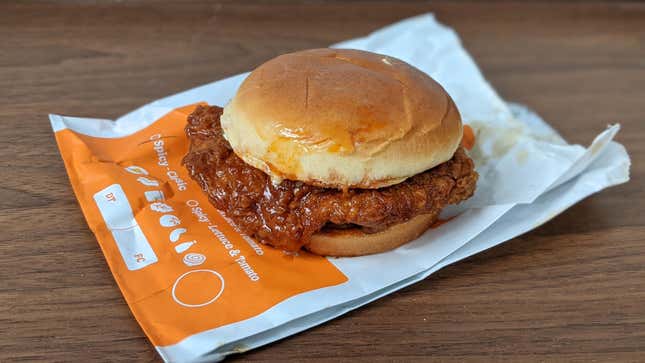 Burger King spicy chicken sandwich sitting on wrapper on wooden surface