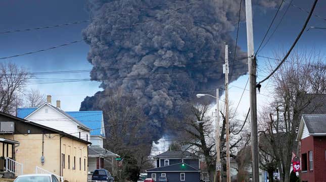 A black plume rises behind a home in East Palestine on Feb. 6, 2023.