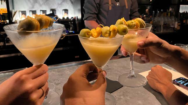 Three glasses being held up in a toast at the bar