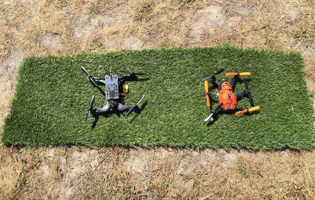 Two FPV drones sitting on some astroturf, waiting to take off.