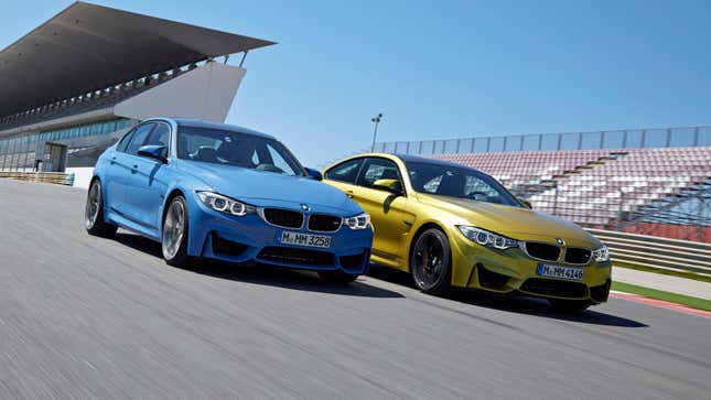 BMW press image of the prior-generation BMW M3 and M4, in blue and gold respectively, on track together, both viewed from the front quarter.