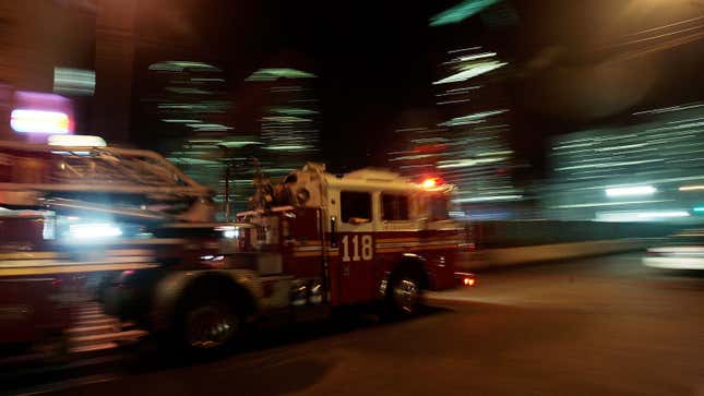A photo of a New York City fire engine responding to an emergency at night. 
