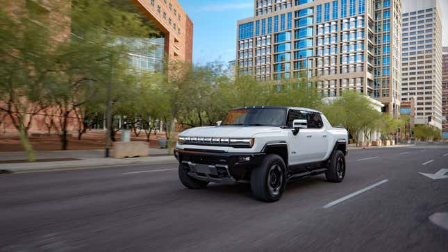 A photo of a white Hummer EV pickup driving on a road. 