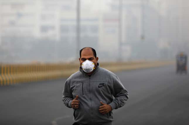 A man wearing a protective mask jogs on a foggy morning in Noida on the outskirts of New Delhi, India, November 14, 2019. REUTERS/Anushree Fadnavis – RC2VAD9BR85X