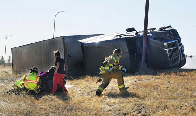 Paramedics tend to an injured person on the onramp of I-25. More than a dozen trucks were blown over by high winds.