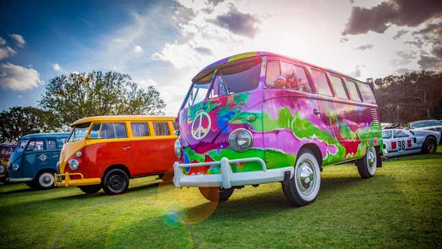 A photo of three Volkswagen buses at a car show. 