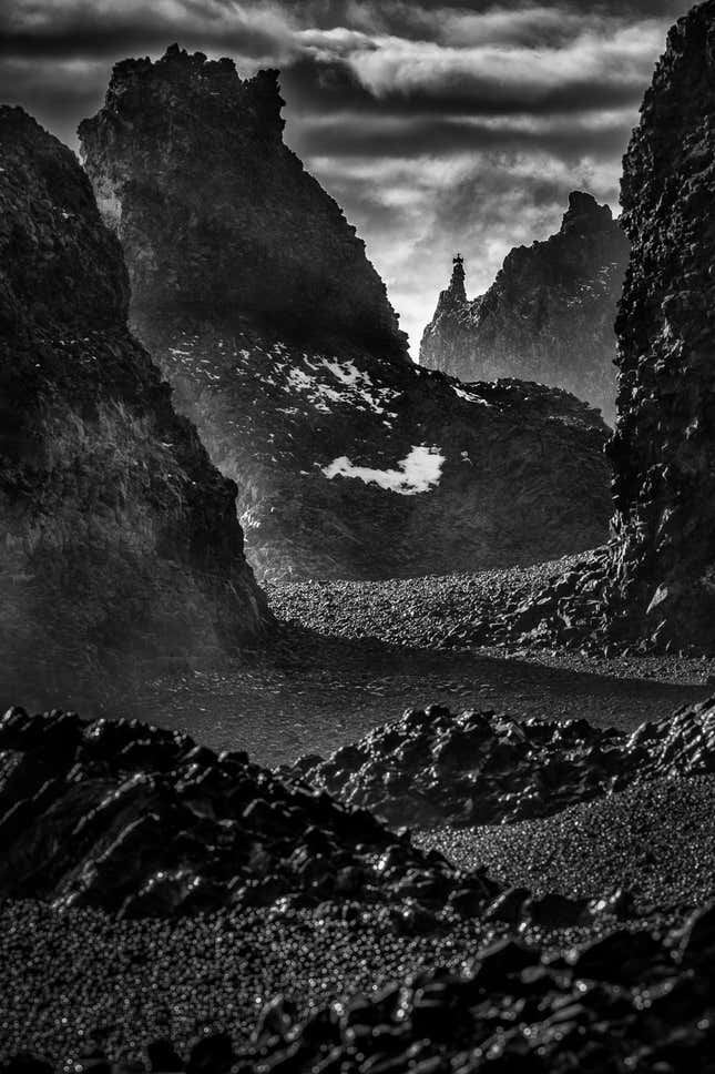 Large volcanic rocks frame a cormorant in this black-and-white image.