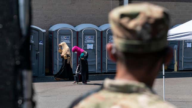 A U.S. soldier watches civilians at a processing center for Afghan refugees at Dulles Expo Center in Chantilly, Virginia on Aug. 24, 2021.