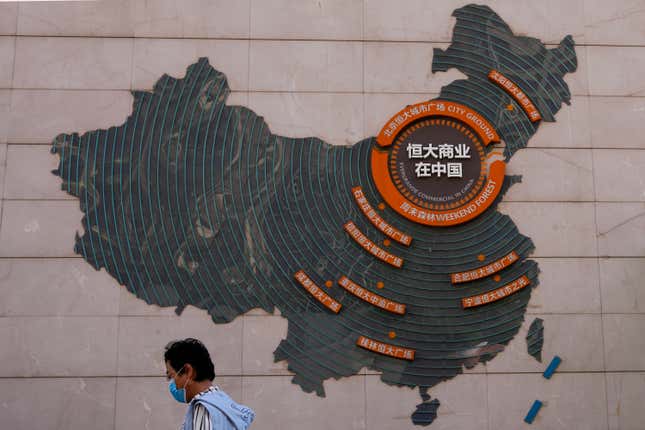 FILE - A woman walks past a map showing Evergrande development projects in China, at an Evergrande city plaza in Beijing on Sept. 21, 2021. Police in a southern Chinese city said on Saturday, Sept 17, 2023 they have detained some staff at China Evergrande Group&#39;s wealth management unit in the latest trouble for the heavily indebted developer. (AP Photo/Andy Wong, File)