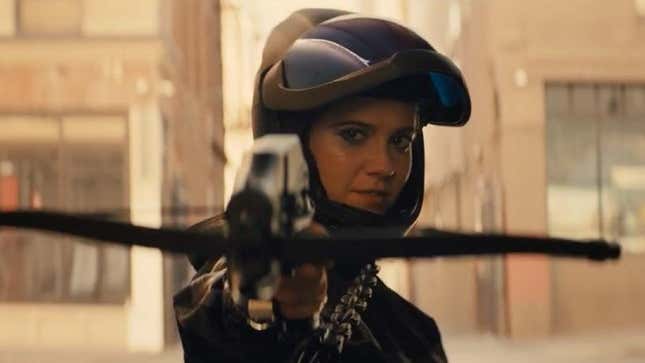 Wearing a motorcycle helmet with the visor up, Huntress (Mary Elizabeth Winstead) fires a crossbow at the camera in a scene from Birds of Prey.