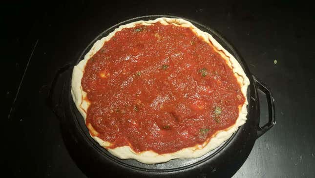 pizza sauce on top of an uncooked pizza