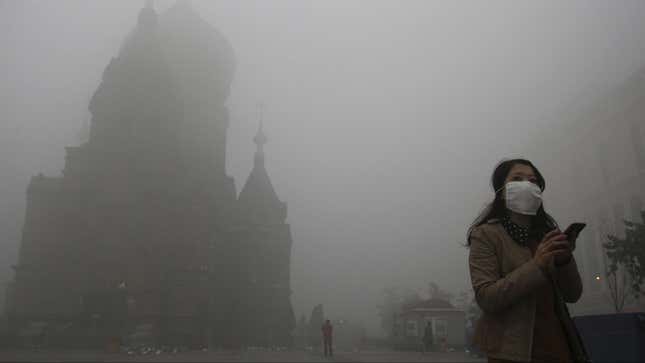 A woman wearing a mask checks her mobile phone during a smoggy day on the square in front of Harbin's landmark San Sophia church, in Heilongjiang province October 21, 2013. The second day of heavy smog with a PM 2.5 index has forced the closure of schools and highways, exceeding 500 micrograms per cubic meter on Monday morning in downtown Harbin, according to Xinhua News Agency. REUTERS/Stringer