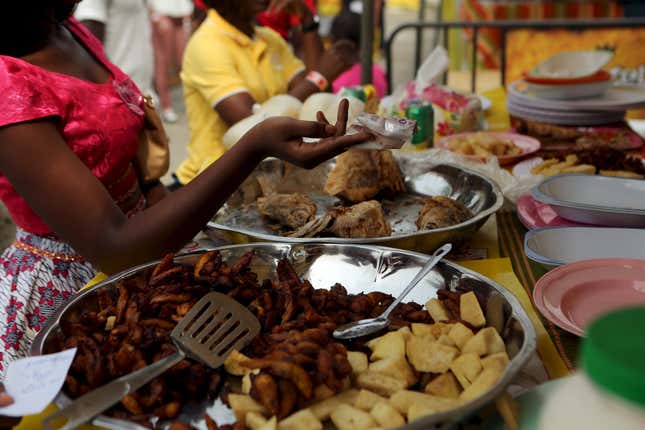 A woman hands over a 10,000 CFA ($16.50) note to pay for food during the attieke and fish festival in Abidjan, Ivory Coast,