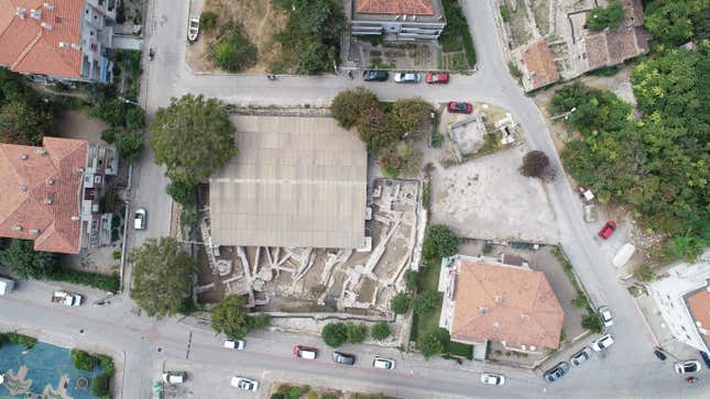 An aerial image of an archaeological site, bordered by modern buildings on all sides.