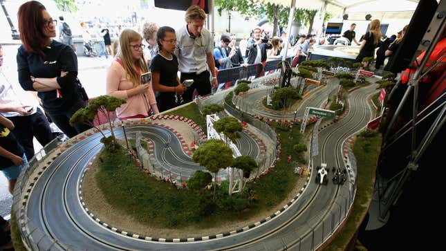 A photo of an intricate slot car race track with two gars going around. 