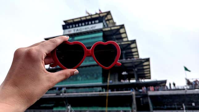 I'm holding my heart-shaped sunglasses in front of the pagoda at the Indianapolis Motor Speedway