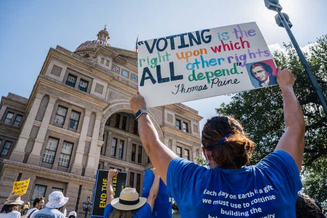 People display signs during the Georgetown to Austin March for Democracy rally on July 31, 2021 in Austin, Texas. Texas activists and demonstrators rallied at the Texas state Capitol after completing a 27-mile long march, from Georgetown to Austin, demanding federal action on voting rights legislation. 