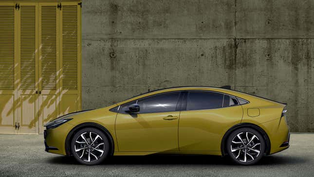 A photo of a yellow Toyota Prius parked near a concrete wall. 