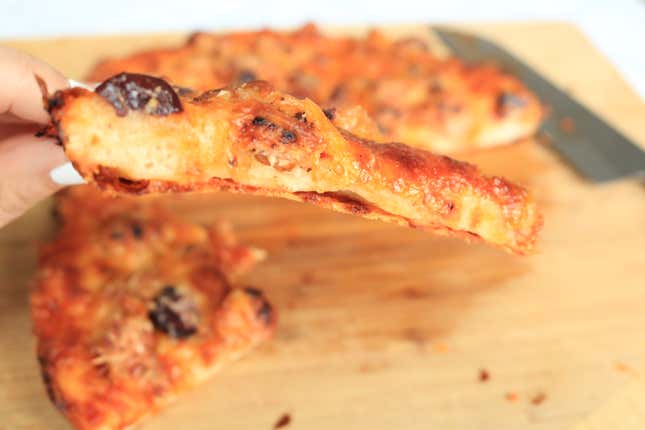 Frico peynir tabakasının görülebilmesi için pizza diliminin yandan görünümü.