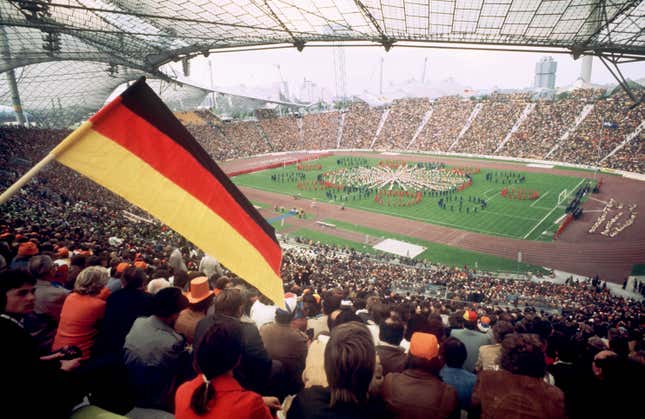 A crowded outdoor stadium with a German flag in the foreground