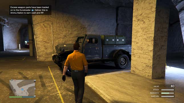 A man in a yellow shirt walks toward a dark green truck in an underground bunker.