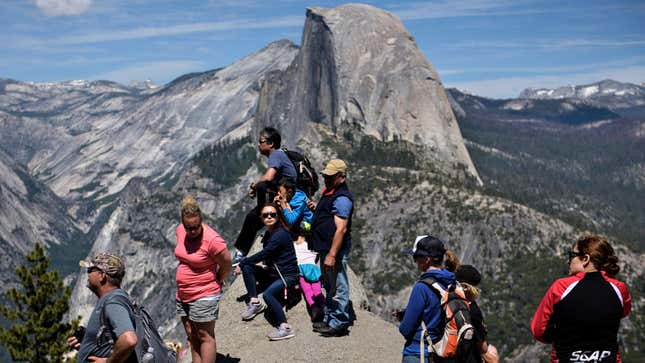 People standing near Glacier Point in Yosemite National Park with Half Dome in the background.