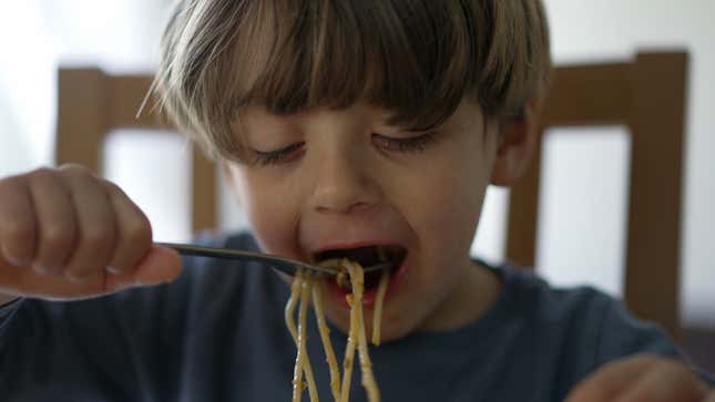 Young boy eating noodles