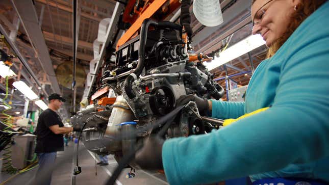 An engineer fits a belt onto a Chrysler engine. 