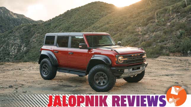 A red 2022 Ford Bronco Raptor is parked on dirt at sunset